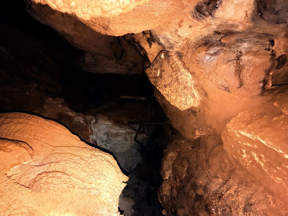 Inside a stalactite cave — warm orange walls and a narrow path. To go deeper is to enter exactly this kind of world: only barely lit, silent rock on every side